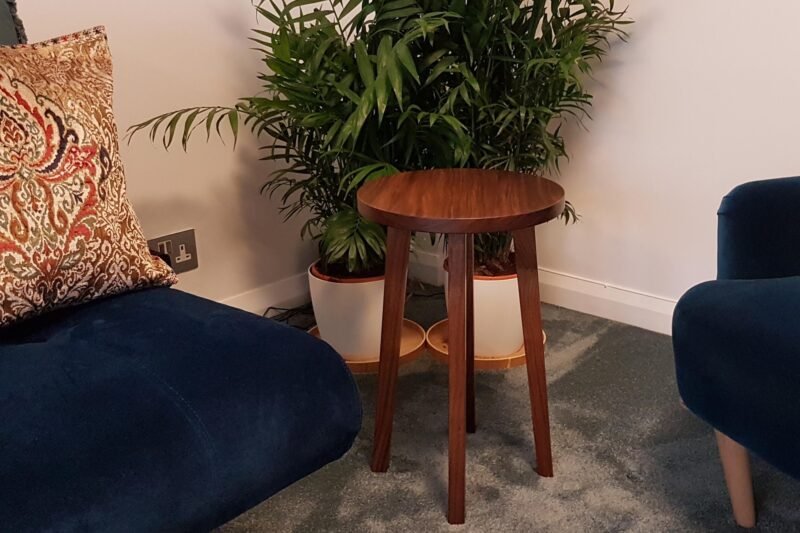 Small walnut side table next to armchair